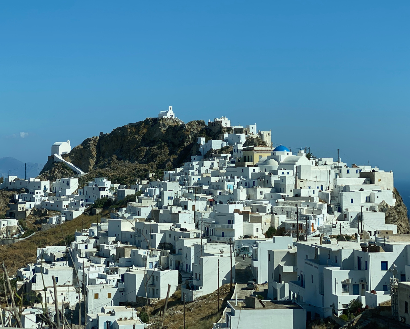 Square white houses clustered on a hill with a chapel at the peak.