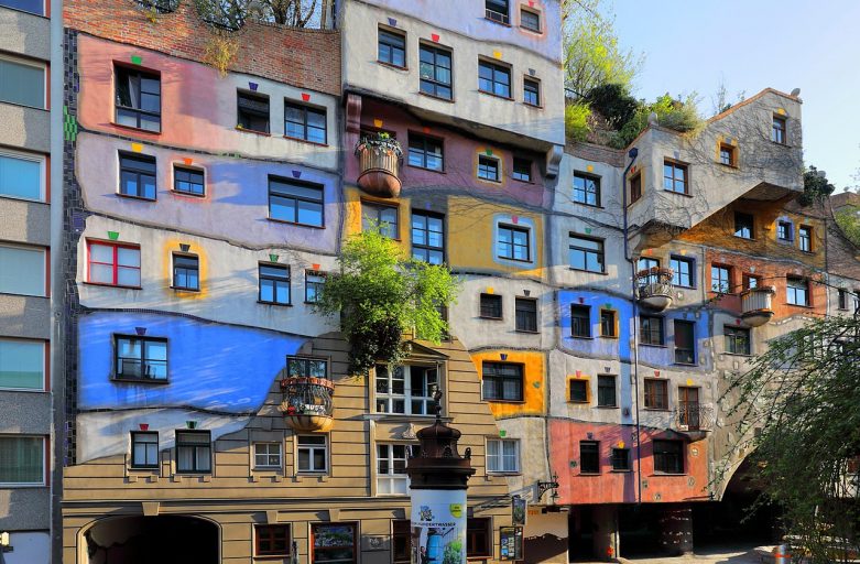 blue, yellow, orange and rose colors stripe across lopsided levels in a surrealist building